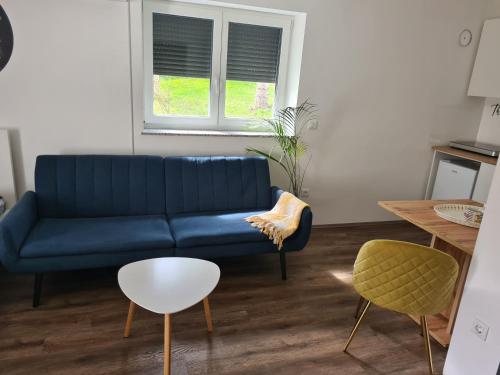 Sofá azul en la sala de estar con ventana en Rooms and apartments Vili en Ptuj
