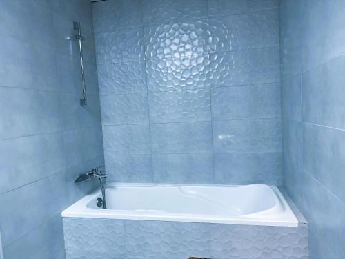 a white bath tub in a bathroom with blue tiles at Dubai Town Jumeirah Beach Residence in Dubai