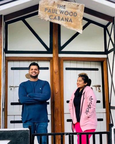 a man and a woman standing on a balcony in front of a building at The Paulwood cabana home stay in Nuwara Eliya