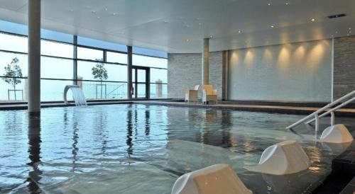 une piscine avec des chaises dans un immeuble dans l'établissement Pleneuf Val André Appart Vue MER 2 Chambres, à Pléneuf-Val-André