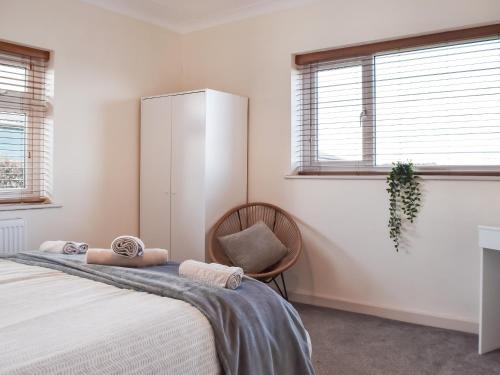 a bedroom with a bed and a chair and windows at Lyncroft Holiday Bungalow in Sandbach