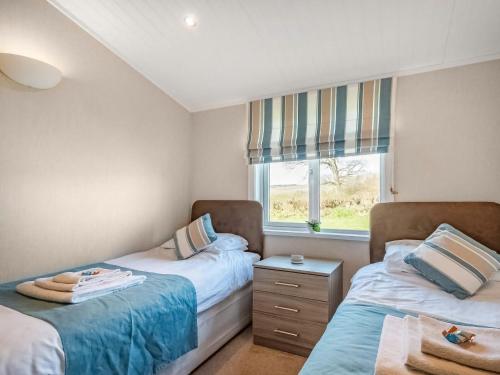 twee bedden in een kleine kamer met een raam bij Oakwood Lodge in Lochwinnoch