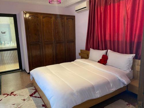 a bedroom with a white bed with a red curtain at اقامة الهام in Casablanca
