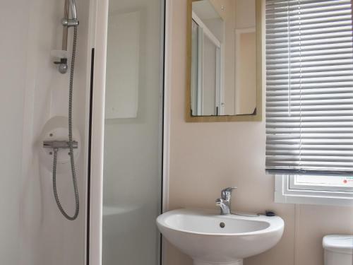 a white bathroom with a sink and a mirror at Meres Retreat in Saxmundham
