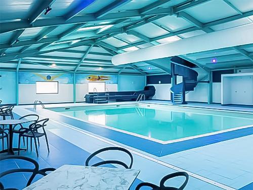 a swimming pool with tables and chairs in a room at Meres Retreat in Saxmundham