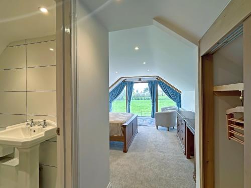 een badkamer met een wastafel, een bed en een raam bij Merrow Cottage in Ledbury