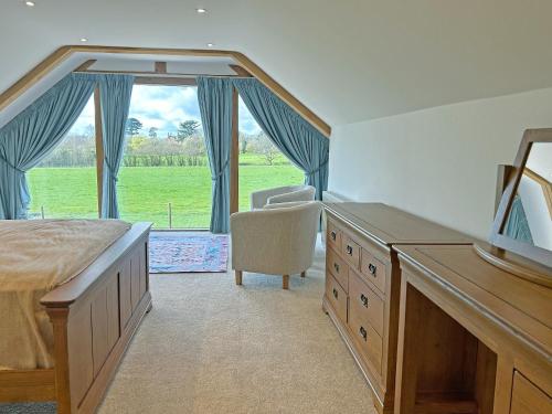 een slaapkamer met een bed, een stoel en een raam bij Merrow Cottage in Ledbury