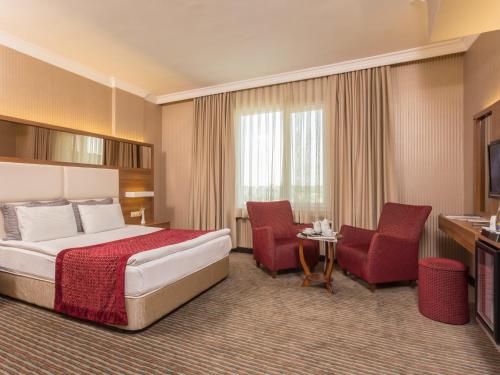 Una habitación de hotel con una cama y dos sillas. en Gazi Park Hotel, en Ankara