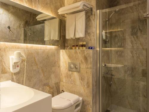 a bathroom with a shower and a toilet and a sink at Gazi Park Hotel in Ankara