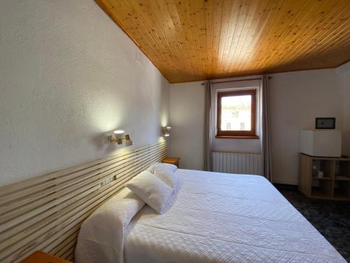 a bedroom with a white bed with a wooden ceiling at Hotel Rural Cal Amadeu in Vilanova de Escornalbou