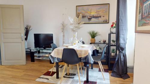 une salle à manger avec une table, des chaises et une télévision dans l'établissement Les Cigognes d'Alsace, à Colmar