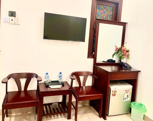 Habitación con 2 sillas, mesa y espejo. en DINH DINH 2 AIRPORT HOTEL en Ho Chi Minh