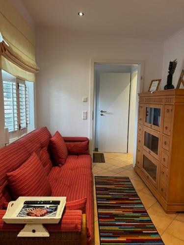 ein Wohnzimmer mit einem roten Sofa und einem Tisch in der Unterkunft Exklusives Refugium- Privat-Boardinghouse Meerbusch - Ihre Oase nahe der Messe Düsseldorf in Meerbusch