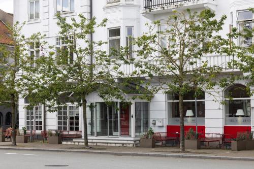 a white building with red doors and windows at Milling Hotel Saxildhus in Kolding