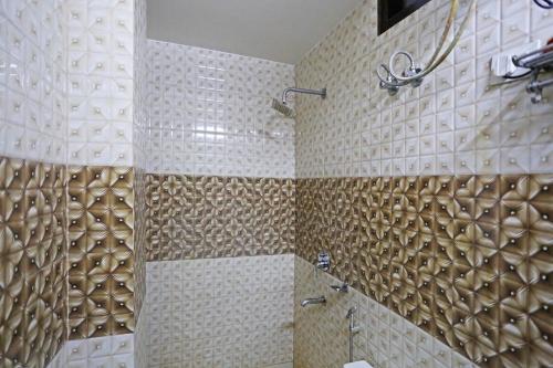 Łazienka wyposażona jest w prysznic ze złotymi i białymi kafelkami. w obiekcie Hotel Star Inn - Delhi Airport, Mahipalpur, Aerocity w Nowym Delhi