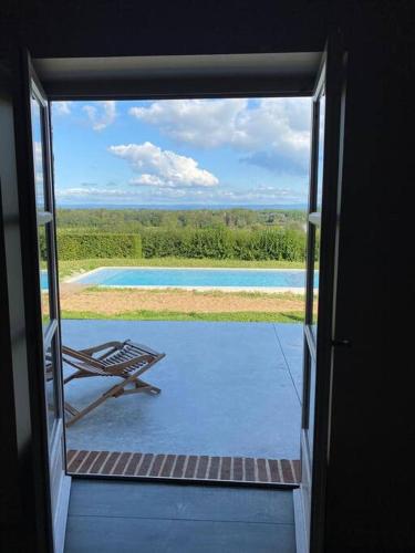 Une porte s'ouvre sur une terrasse avec un banc extérieur. dans l'établissement Longère de château en Bourgogne - avec piscine, à Saint-Germain-du-Bois