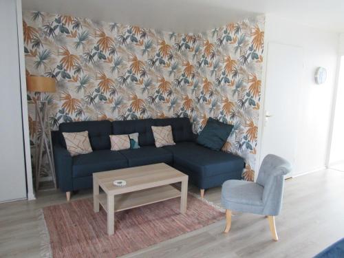 uma sala de estar com um sofá azul e uma cadeira em Appartement 3 pièces proche Disneyland em Magny-le-Hongre