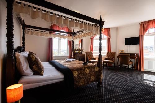 a bedroom with a canopy bed and a desk at Milling Hotel Saxildhus in Kolding