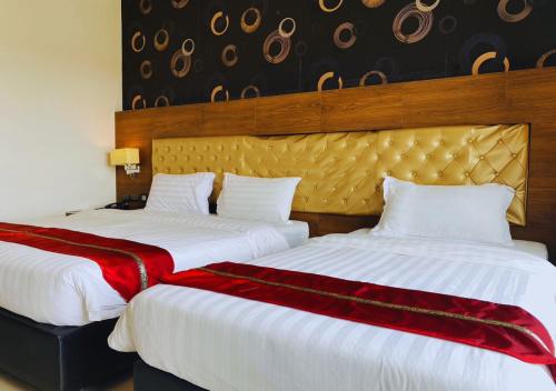 two beds in a hotel room with red and white sheets at Constancy Pattaya Hotel Jomtien in Na Jomtien