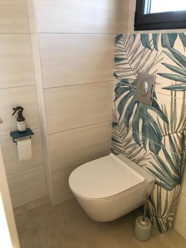une salle de bain avec toilettes et un papier peint tropical dans l'établissement Nadia Residences de la mer 