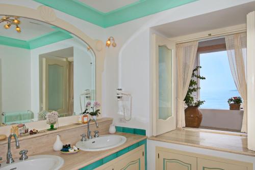 La salle de bains est pourvue de 2 lavabos et d'un grand miroir. dans l'établissement Villa Santa Chiara Positano Suites, à Positano