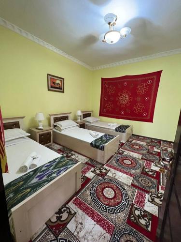 een kamer met drie bedden en een tapijt bij Hotel ISMOIL SAMONI in Bukhara
