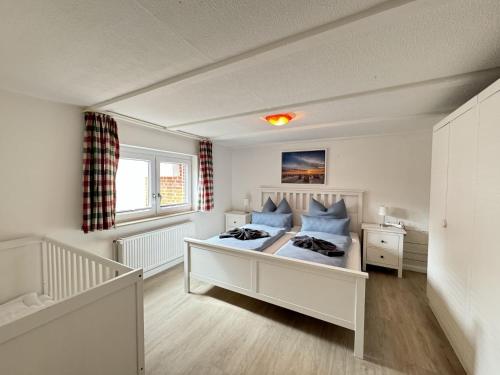 a white bedroom with a bed and a window at Führs in Borkum