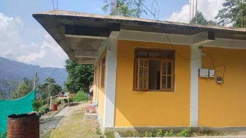 een geel huis met een raam aan de zijkant bij Sittong retreat in Karsiyang