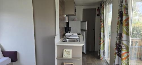 uma pequena cozinha com um lavatório num quarto em MOBIL HOME CAMPING LES SABLES DU MIDI em Sérignan