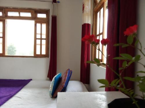 a room with a bed and two windows with red curtains at Sittong retreat in Karsiyang