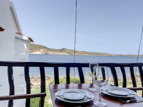 a table with a glass of wine on a balcony at P107 Un rinconcito en el mar in Fornells
