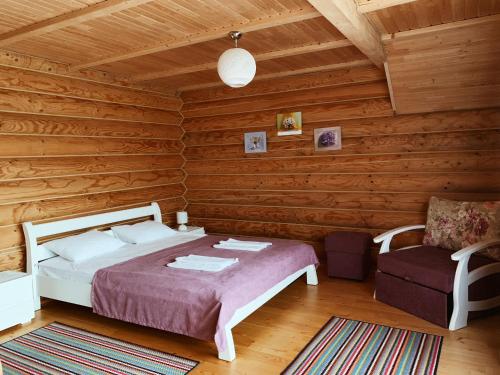 a bedroom with a bed and a chair in a log cabin at Cottage Simka in Mykulychyn