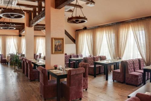 un restaurant avec des tables et des chaises dans une salle avec des fenêtres dans l'établissement Felisa Hotel, à Kharkov