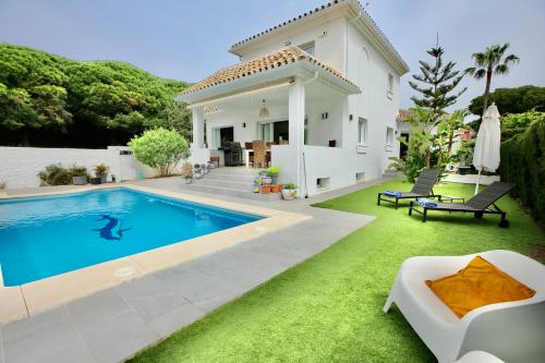 a villa with a swimming pool in front of a house at Sapore di mare Luxury B&B and Cooking in Marbella
