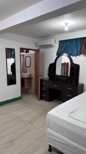 a bedroom with a bed and a dresser and a mirror at The Wave Hostel Corn Island in Corn Island