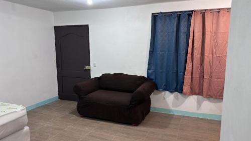 a brown chair sitting in a room with curtains at The Wave Hostel Corn Island in Corn Island