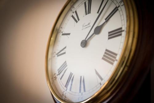 a gold clock with roman numerals on a wall at The Old Vicarage in Bridgnorth