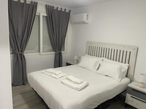 een slaapkamer met een wit bed en 2 handdoeken bij Apartamentos Azonaicas Centro Tendillas in Córdoba