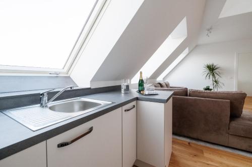 an attic kitchen with a sink and a couch at SYMPHONY Apartments 39 - Modern Loft with Terrace and Grill in Central Location in Vienna