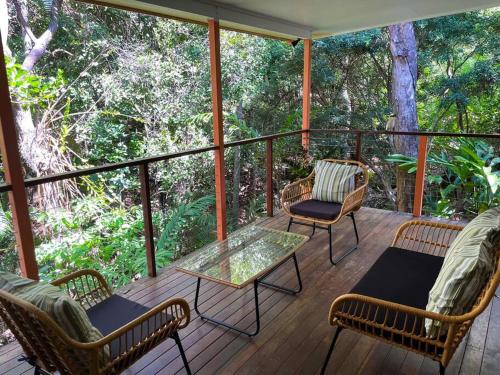 een afgeschermde veranda met stoelen en een tafel bij The Treehouse at Alma Bay in Arcadia