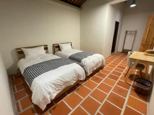two beds sitting in a room with a room with a table at Sunshine Music Traditional Guesthouse in Jinsha