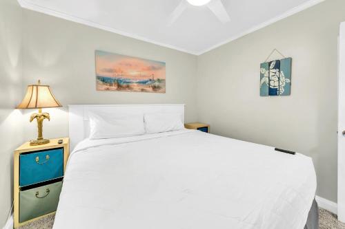 a bedroom with a white bed and a lamp at Misty Harbour 7 in Panama City Beach
