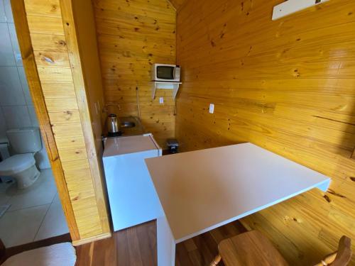 グラマドにあるCabanas Encantos da Naturezaの木製の部屋のキッチン(白いテーブル付)