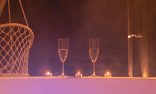 two glasses of champagne sitting on a table with candles at Cabañas O Recuncho do Sor in O Barqueiro