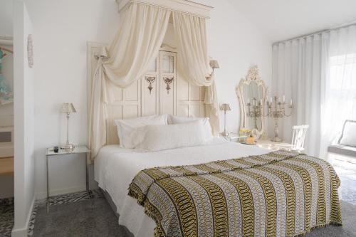 a white bedroom with a large bed with a canopy at CoimbraAmeias in Coimbra