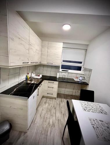 cocina con armarios blancos, mesa y ventana en Amore Lux en Paraćin