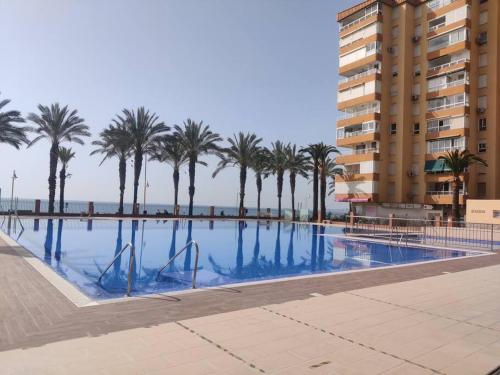 ein Pool mit Palmen und ein Gebäude in der Unterkunft Algarrobo Costa luxury apartment POMELO , seafront in Algarrobo-Costa