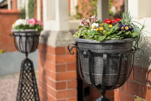 two flower pots are hanging on a brick wall at The Old Vicarage in Bridgnorth