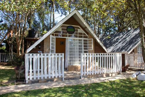 una pequeña casa con una valla blanca en Camp Mahon Gardens, en Nanyuki