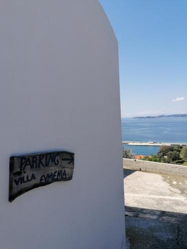 a sign on the side of a white wall with the ocean at Villa Evmenia Panoramic sea view & Sea front apartments in Skopelos Town